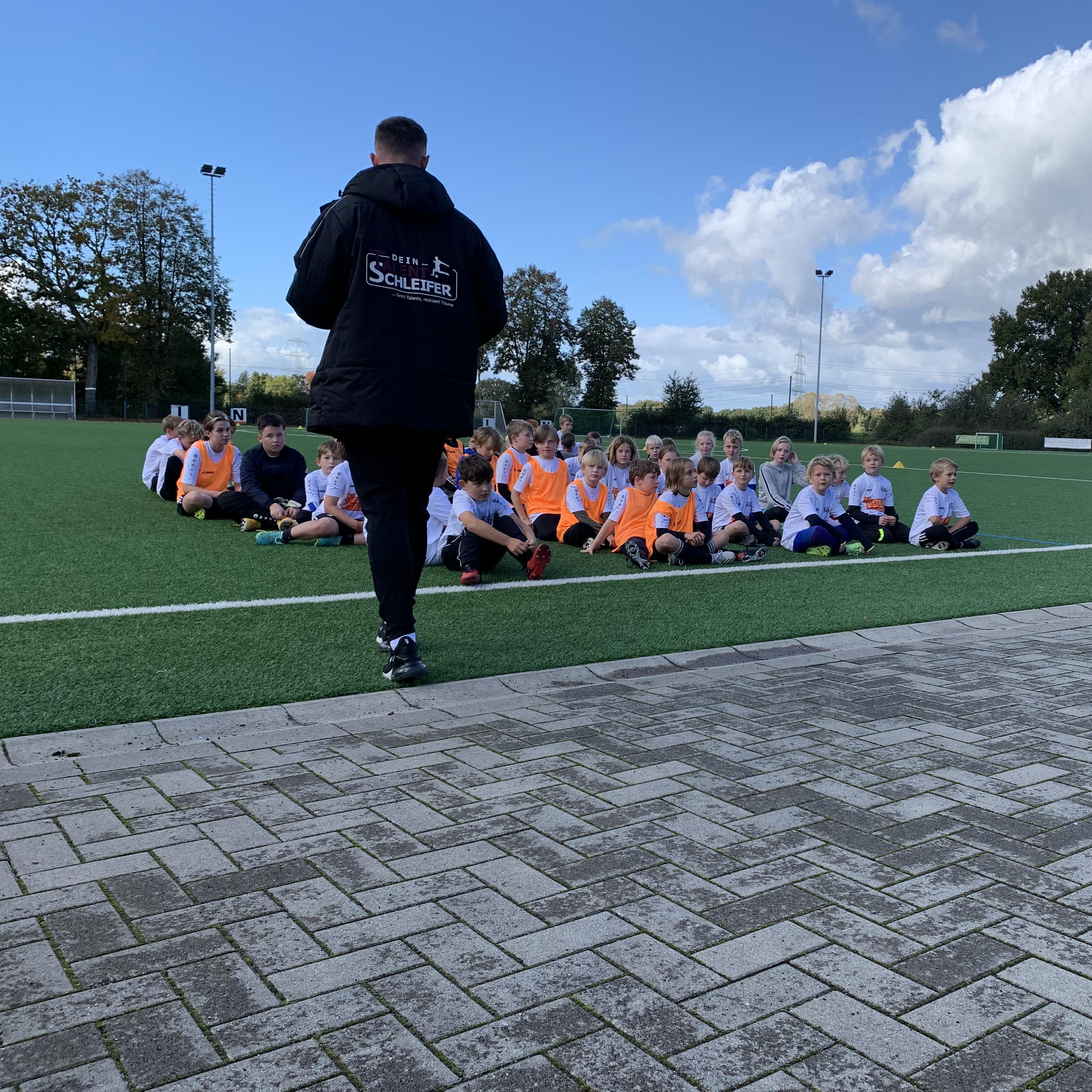 Trainer vor Spielergruppe